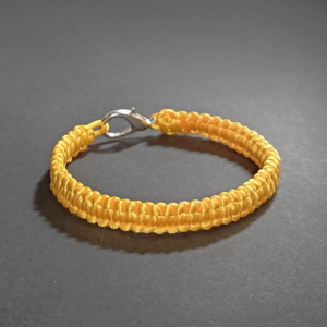 Bransoletka dziewczęca lub damska żółta wypleciona ze sznurka jubilerskiego. Obwód wewnętrzny bransoletki 15cm.